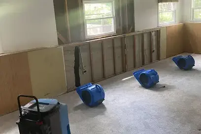 Air movers and a dehumidifier drying a room with the lower drywall removed