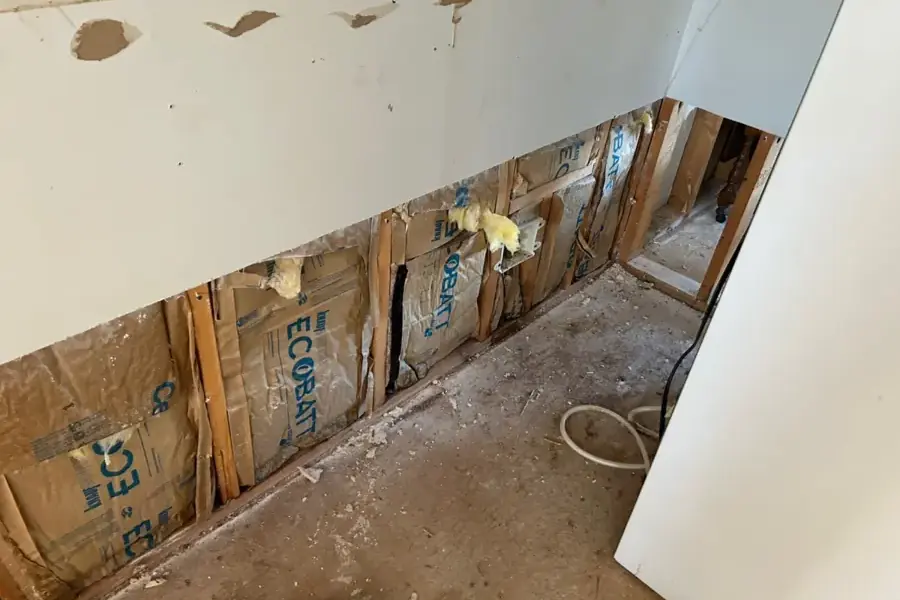 Drywall cut away to expose wet insulation and wall framing