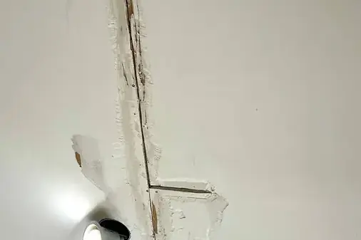 Water stain and crack running along a ceiling seam