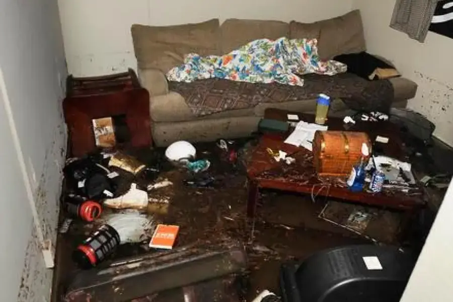 Mud and soaked belongings left in a living room by floodwater, storm flood cleanup in Spring Hill, TN